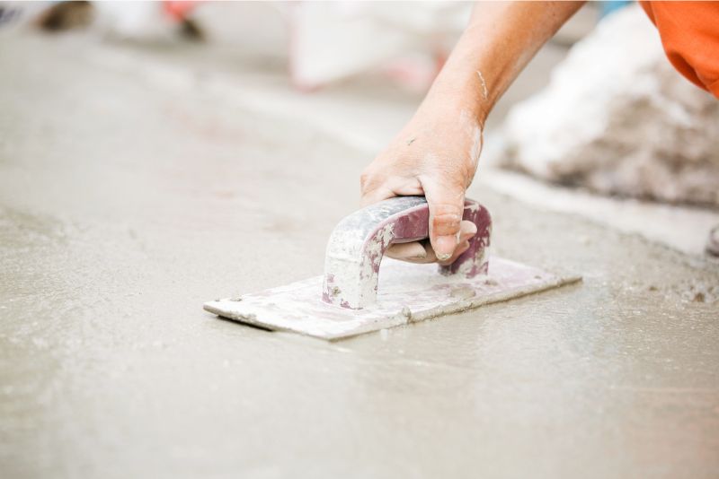 A concreter’s hand smoothing a freshly poured slab with a bull float on a Hervey Bay site