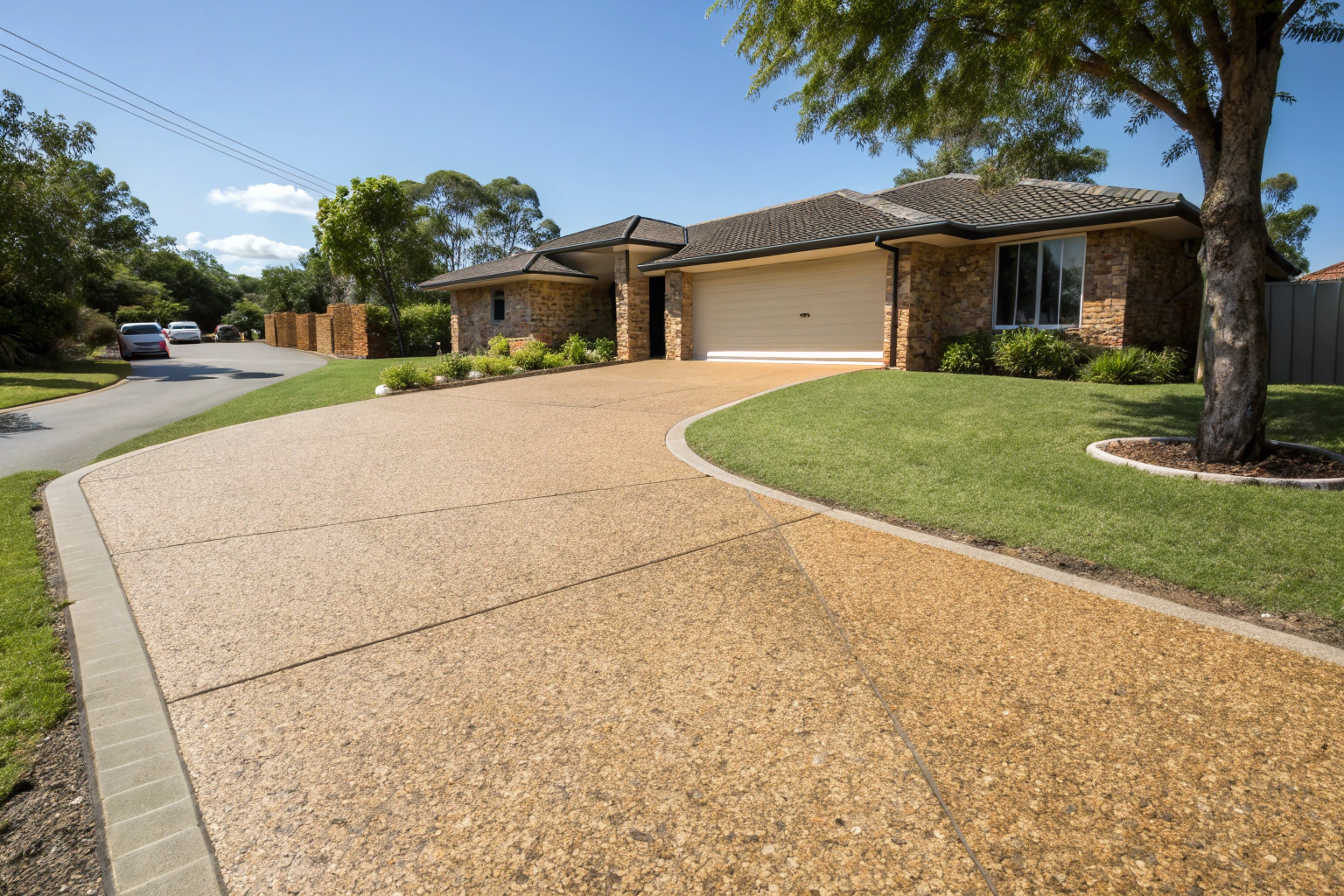 Wide-angle view of a freshly sealed exposed aggregate driveway on a Hervey Bay property